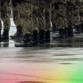 Rows of military boots standing in formation on wet pavement, reflections visible in the rain