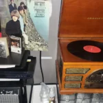 A Crosley record player with The Rolling Stones Big Hits record spinning on the turntable surrounded by CDs and records